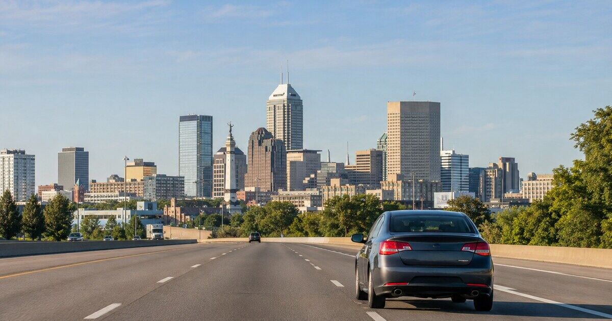 Car traveling toward the Indianapolis skyline on an Indiana highway